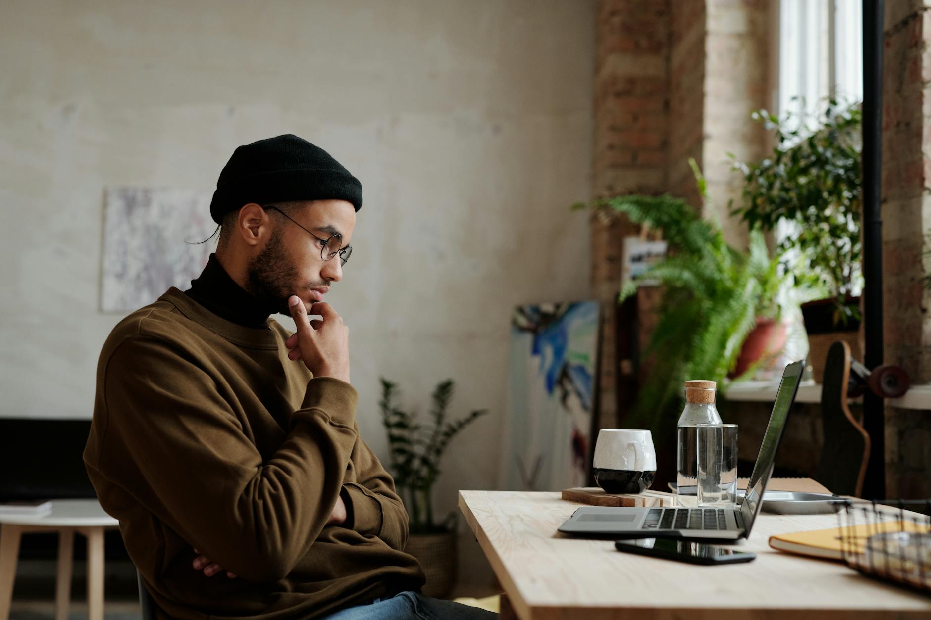 A man working thoughtfully on a laptop in a relaxed setting, reflecting the daily effort adults with ADHD put into focused work
