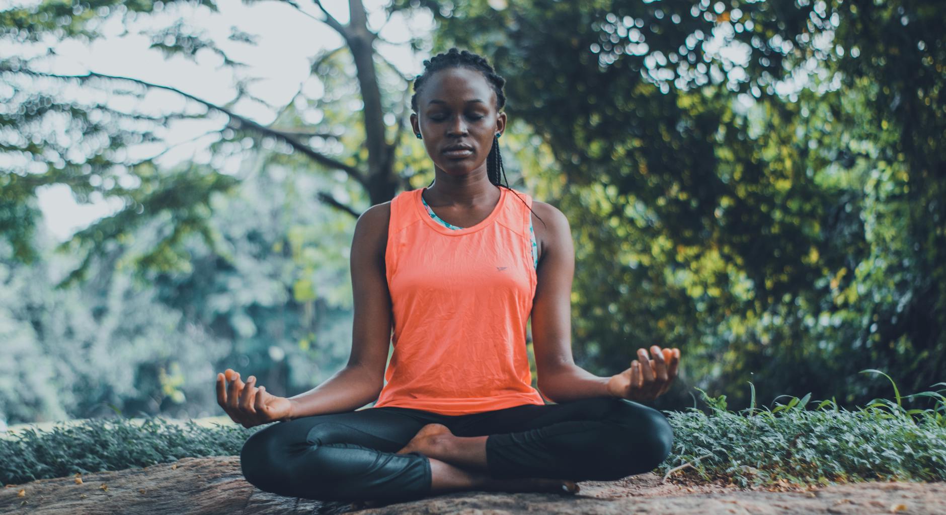 A woman practicing meditation outdoors in a lush green setting, illustrating how lifestyle practices like mindfulness can complement ADHD treatment